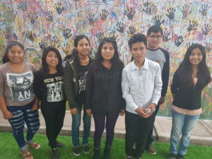Group of students from Peru standing in front of painted mural at school